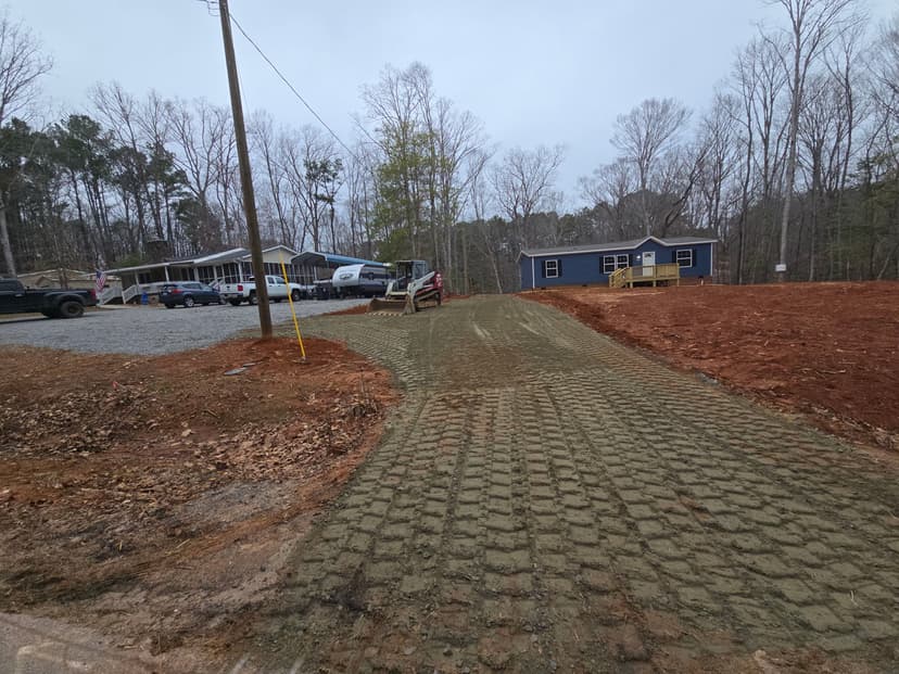 Newly constructed gravel driveway leading to residential homes in wooded area.
