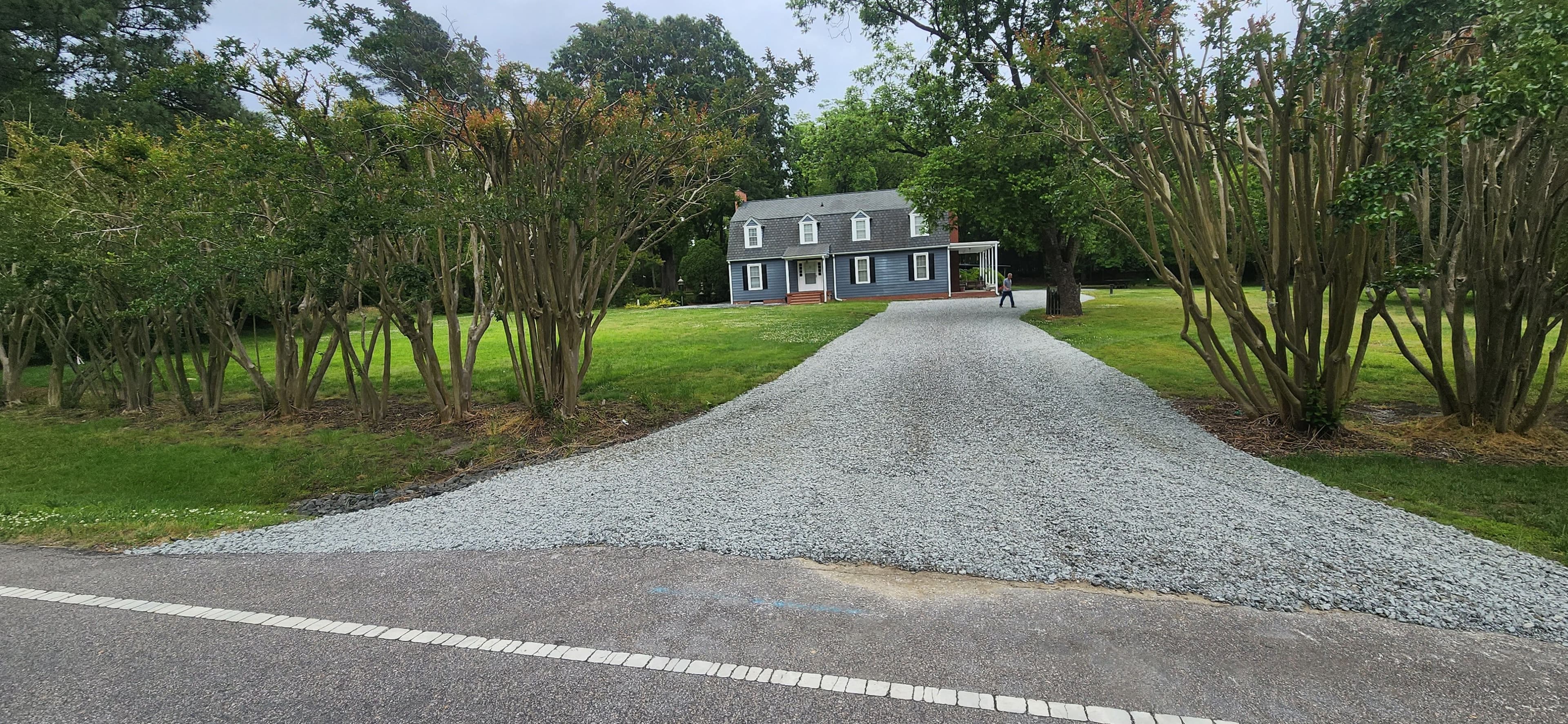 Finished gravel driveway with clean stone surface leading to landscaped property