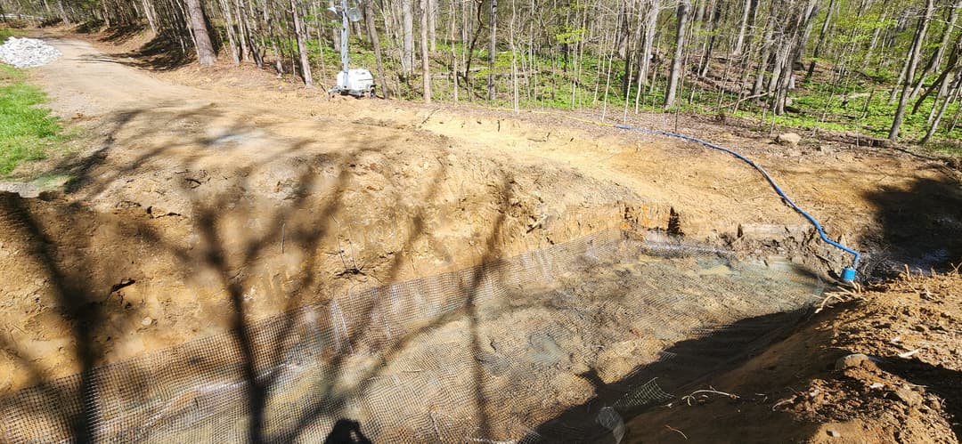 Excavated area in a forested setting with a water drainage system installed.