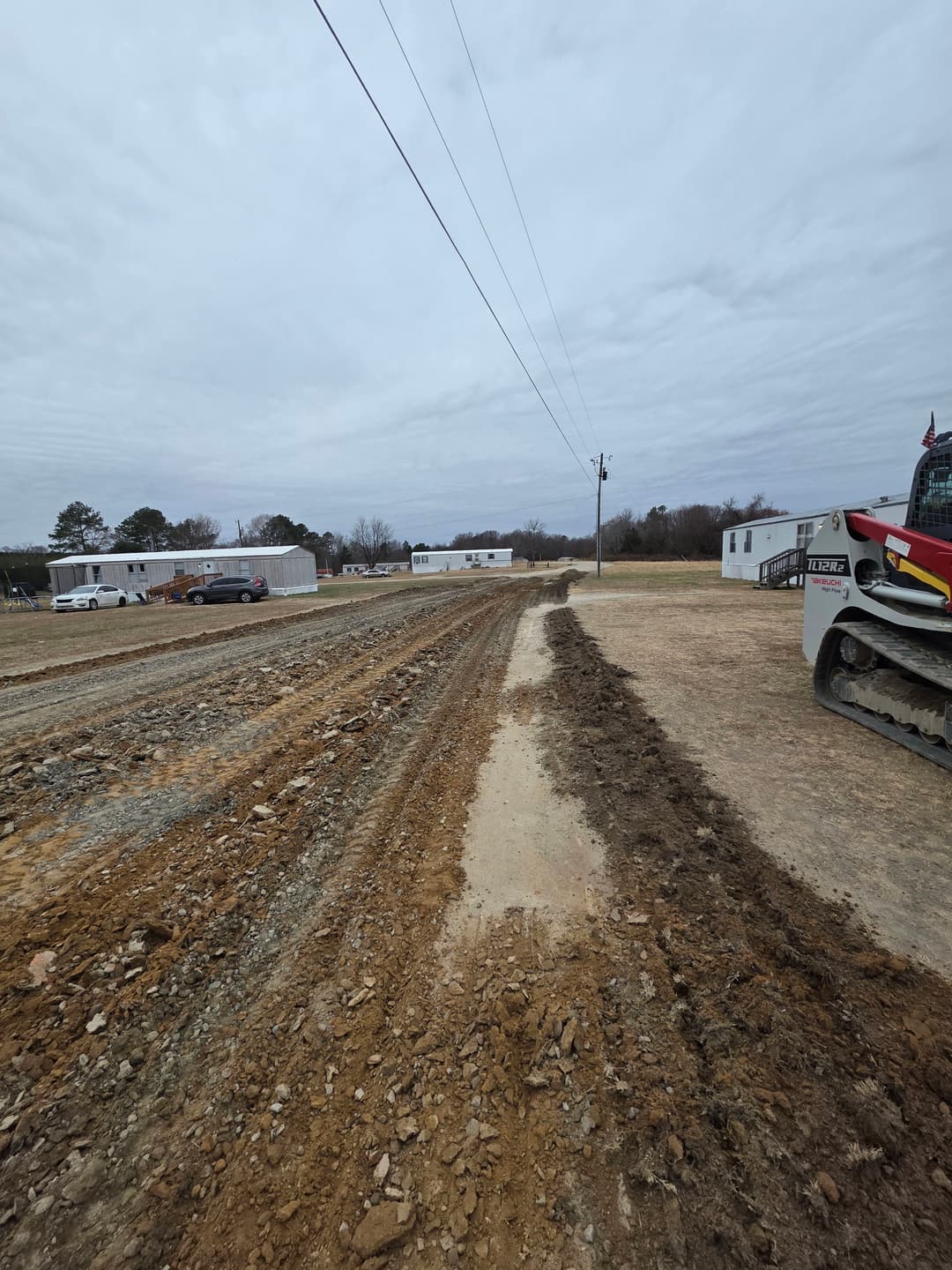 Construction site with dirt roads and heavy machinery under a cloudy sky.