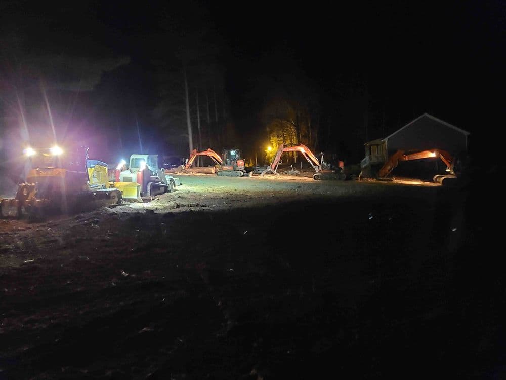 Construction site at night with heavy machinery and illuminated work area.
